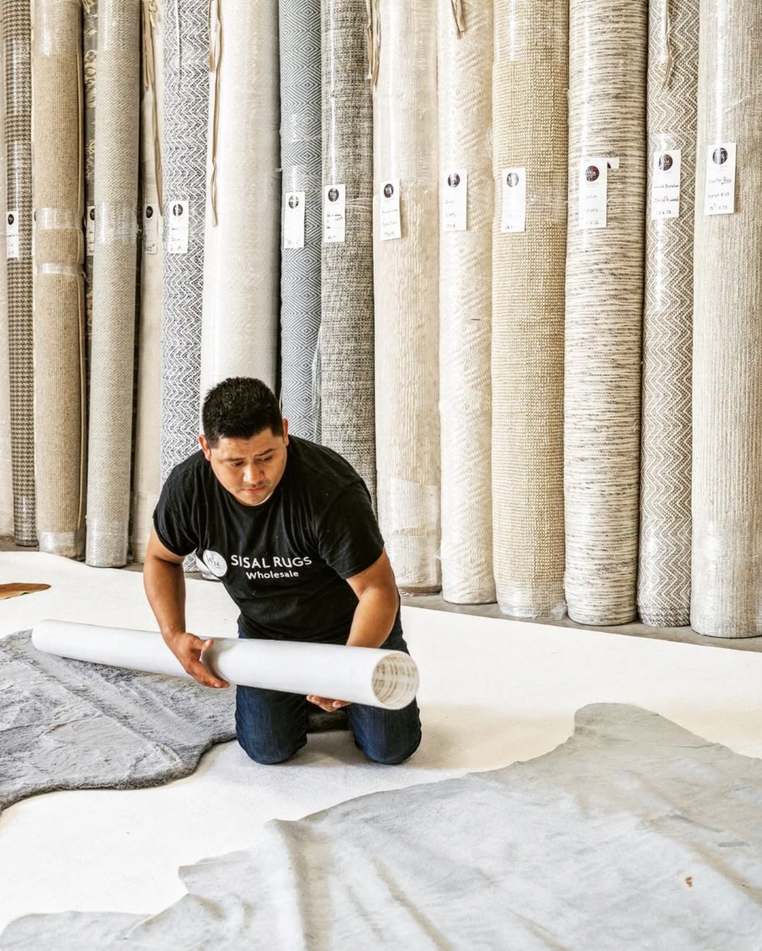 Owner hand-rolling a custom rug in the showroom